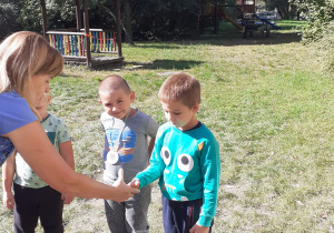 nauczycielka podaje rękę dziecku podczas uroczystości pasowania na przedszkolaka