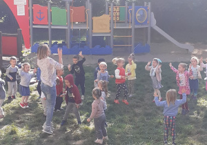 dzieci z nauczycielką tańczą w ogrodzie przedszkolnym