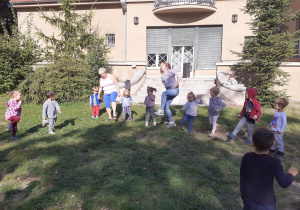 dzieci z nauczycielką tańczą w ogrodzie przedszkolnym