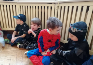 czterech chłopców przebranych w stroje karnawałowe siedzą na podłodze