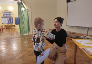 Nauczycielka wręcza nagrodę chłopcu, który zajął III miejsce.