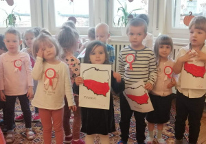 grupa dzieci prezentuje rysunki na których jest kontur mapy Polski w kolorze biało-czerwonym