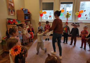 Nauczycielka tańczy z dziewczynką, dookoła dzieci formują koło.