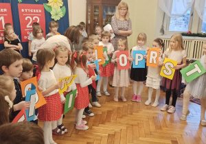dzieci stoją z literkami z alfabetu