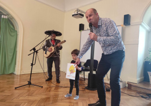 Chłopiec z grupy 1 trzyma portret Speedy Gonzaleza a Pan Maciej śpiewa piosenkę "Speedy Gonzalez"