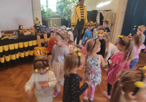 Dzieci z grupy 1 i 2 biegają po sali przebrane za pszczółki