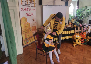 Dziewczynka z grupy 1 przebrana za królową pszczół siedzi na krześle