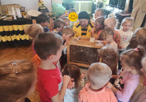 Dzieci z grupy 1 i 2 oglądają żywe pszczoły zamknięte w przenośnym ulu i słuchają Pana Tomasza