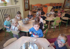 Dzieci z gr 2 siedzą przy stolikach i kroją owoce na salatkę owocową