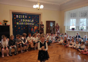 Dziewczynka z gr 2 mówiąca wierszyk na tle dzieci z naszego przedszkola