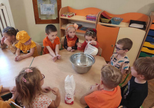 Dzieci z gr 2 wsypujące do miski mąkę na ciasto