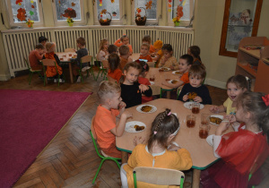 Dzieci z gr 2 siedzące przy stolikach i konsumujące ciasto dyniowe