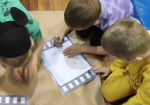 Dzieci z grupy 5 rysują bajki na kartonie