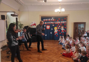 Dzieci z przedszkola słuchają utworu, granego na skrzypcach