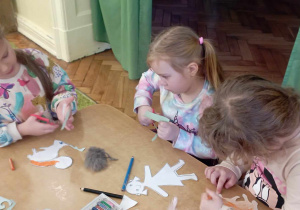 3 dziewczynki z grupy 4 wycinają sylwety z papieru