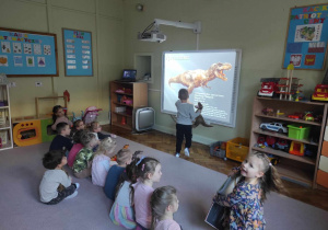 Dzieci z grupy 2 oglądają prezentację multimedialną o dinozaurach