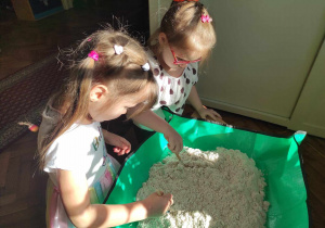 2 dziewczynki z grupy 2 szukają w piasku dino-skamielin