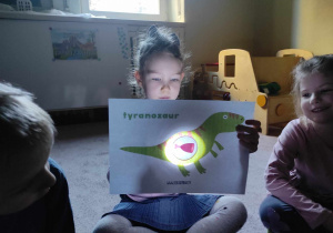 Dziewczynka z grupy 2 ogląda co je dinozaur dzięki latarce
