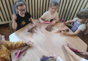 Dzieci przy stolikach rozczesują szczotkami szurek