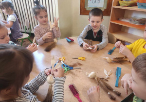 Dzieci przy stolikach przyczepiają uszy do zajączka